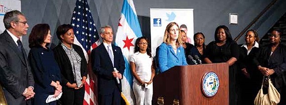 Marie Lynch (at podium), owner and founder of Skills for Chicagoland's Future speaks at Skills event, with Mayor Rahm Emanuel (centered behind Lynch), and Skills candidates on the right. The program has partnered with 50 local businesses to find jobs for unemployed residents of Cook County. Since 2012, Skills has hired more than 3,000 people. 