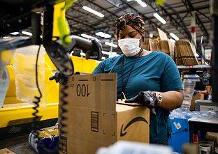 Woman in PPE preparing an Amazon package